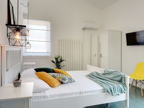 Una camera da letto con un letto, un comodino e una TV appesa al muro.