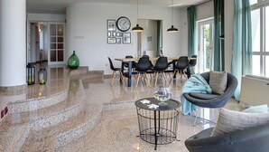A spacious living area with a dining table, chairs, a sofa, and a large window with curtains. - Villa in Medulin With Garden, Private Pool and Sauna Near the Center (Medulin)