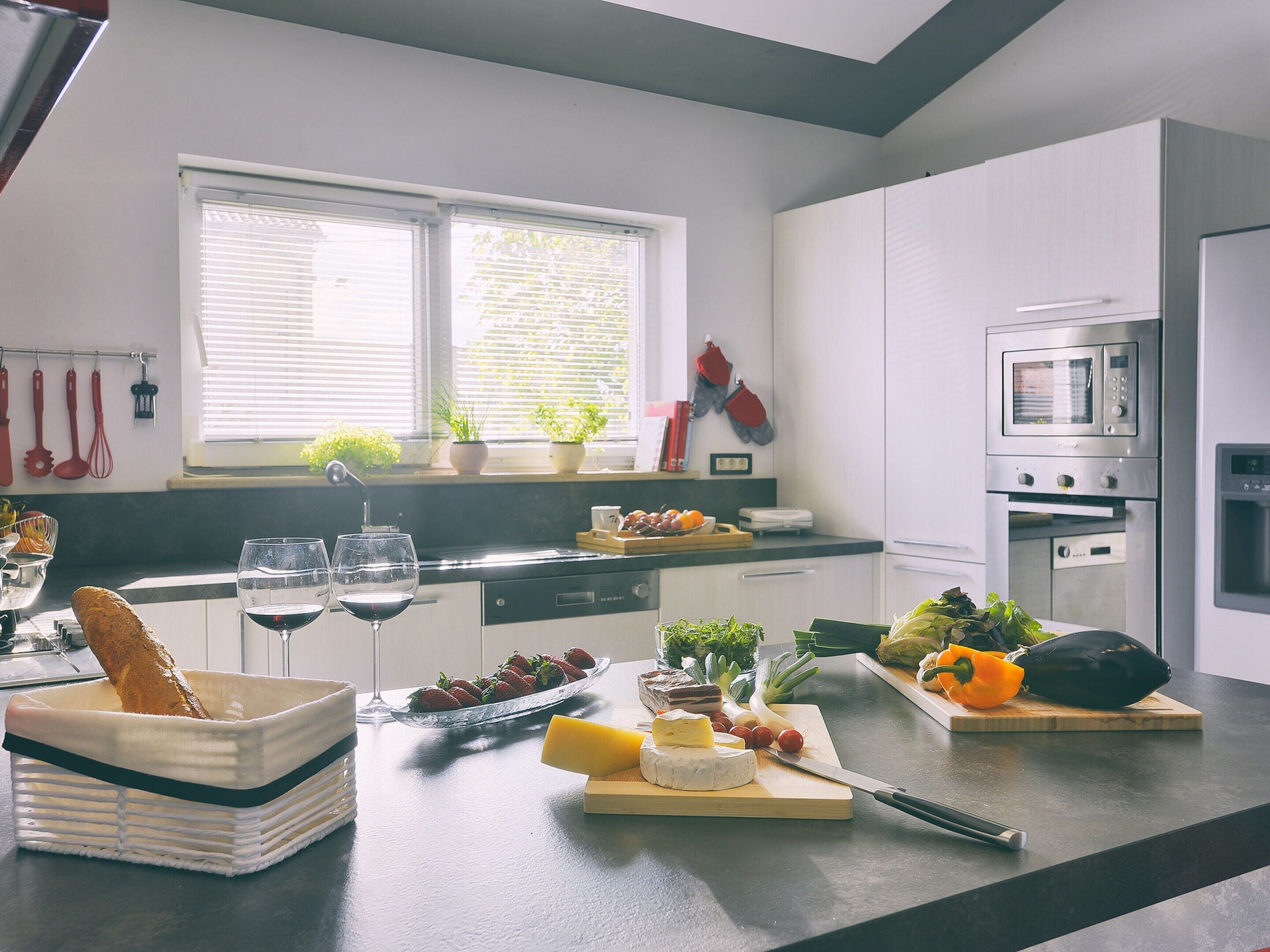 A modern kitchen with a window, white cabinets, a microwave, and various food items on the counter.