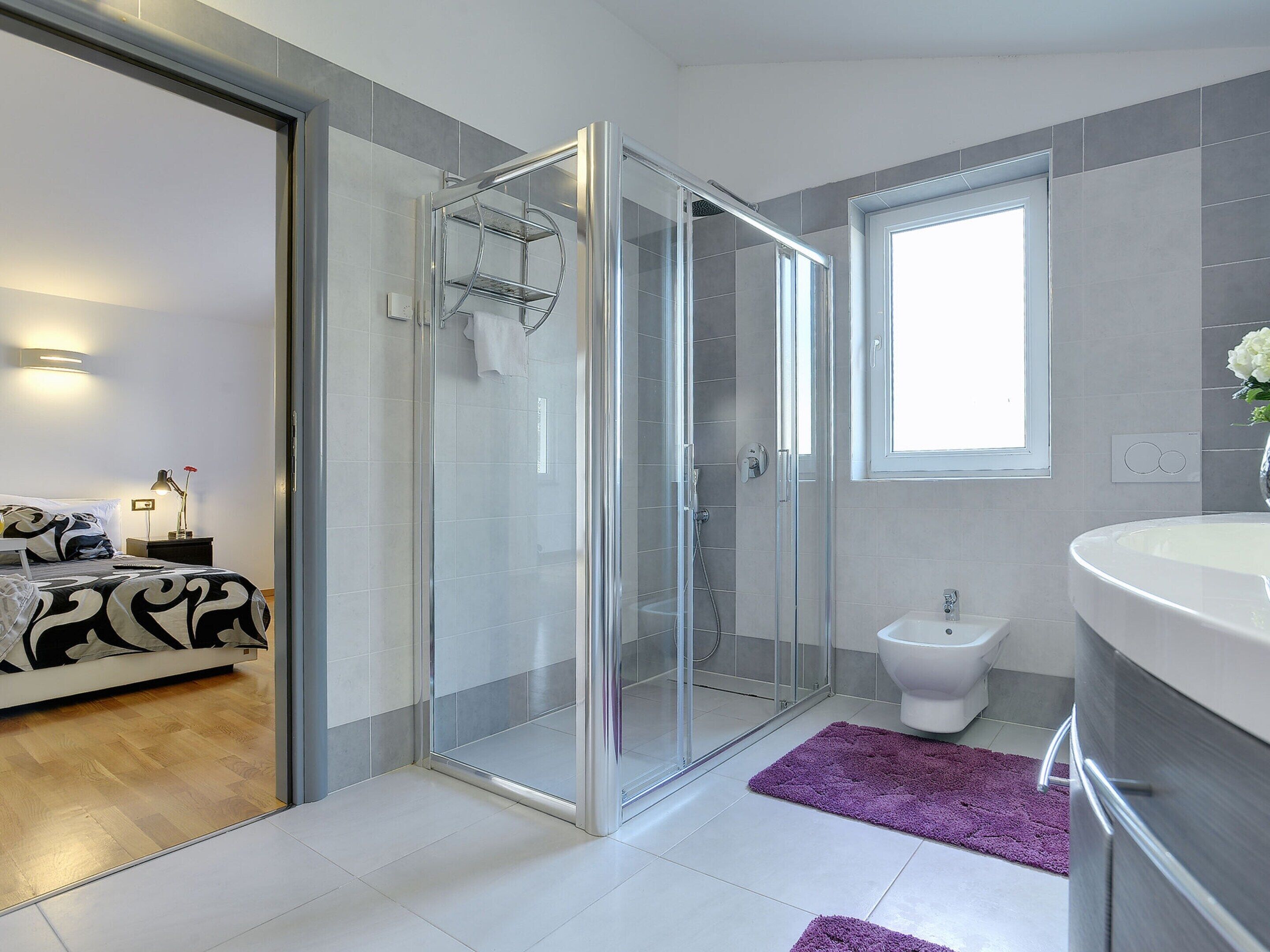 Un bagno moderno con cabina doccia in vetro, un water e un lavandino.