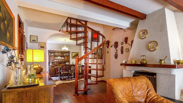 Un vaste salon doté d’un escalier en bois, d’un coin repas et d’une cuisine.