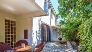 Une terrasse dotée de meubles en osier, d’un sol en pierre et d’un petit barbecue.