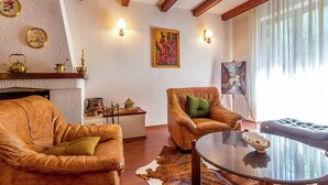 Un salon avec des canapés en cuir, une table basse en verre, une cheminée et un tableau au mur.