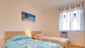 A bedroom with a wooden bed, a nightstand, a lamp, a painting of a beach, and a window with sheer curtains. - Detached 6 Bedroom House with Private Pool near Ližnjan (Liznjan)