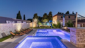 Ein Poolbereich mit Liegestühlen und einer Steinmauer mit dem Schriftzug 'VILLA ISTAN KAMEI'.