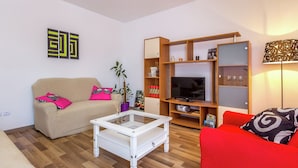 Un salon avec un canapé beige, un canapé rouge, une table basse blanche et un meuble TV avec des étagères.
