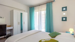 Une chambre à coucher avec un lit, une armoire, un bureau et une fenêtre avec des rideaux.
