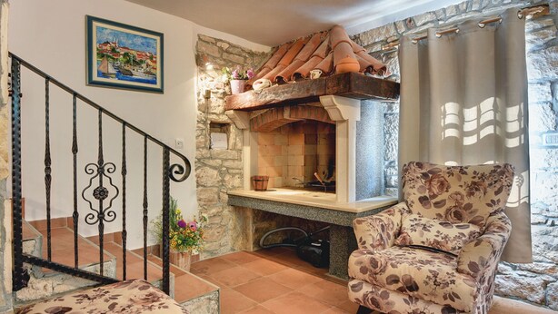 Una sala de estar acogedora con chimenea, un sillón estampado y una escalera con barandilla de metal.