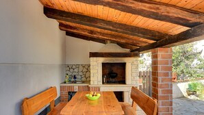 Un patio al aire libre con mesa y bancos de madera, un frente de piedra y un horno de ladrillo.
