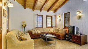 A cozy living room with wooden beams, a sofa set, a coffee table, and a television. - Holiday Home With Swimming Pool, Near the Center (Liznjan)