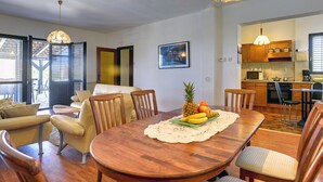 A dining area with a wooden table, chairs, and a fruit centerpiece. - Holiday Home With Swimming Pool, Near the Center (Liznjan)