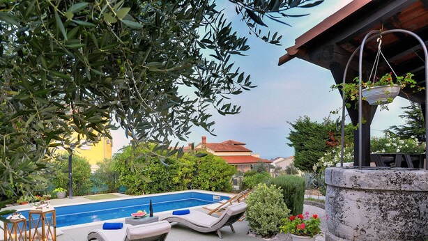 A swimming pool with lounge chairs, a stone wall, and potted plants. - Holiday Home With Swimming Pool, Near the Center (Liznjan)