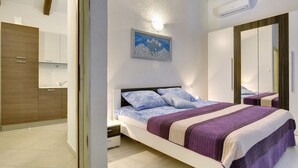 A bedroom with a bed, a nightstand, a painting, a wardrobe, and a bathroom with a sink and cabinets. - Villa in Lupoglav With Pool Near the Sea (Lupoglav)