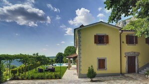 A yellow building with a stone-paved courtyard, a swimming pool, and a view of the sea. - Villa in Lupoglav With Pool Near the Sea (Lupoglav)