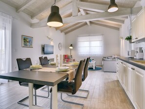 Un comedor con una mesa de madera, sillas y un televisor montado en la pared.