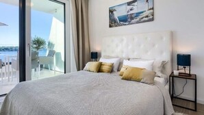A bedroom with a large bed, a view of the sea, and a painting of a lighthouse on the wall. - Villa in Pula With Private Swimming Pool (Medulin)