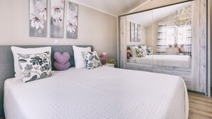 Un dormitorio moderno con una cama grande, un espejo y obras de arte en la pared.