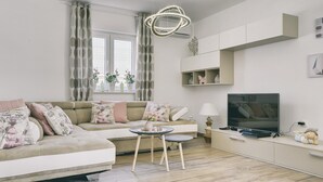 Una sala de estar moderna con un sofá, televisión y una pequeña mesa con adornos.