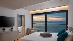 A modern bedroom with a large bed, a TV, and a view of the sea. - Beach Villa in Korcula with Pool, Sauna & Hot Tub (Blato)