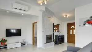 A modern living room with a flat-screen TV, grey sofas, a fireplace, and a hallway leading to a bedroom. - Modern Holiday Home With Pool in Pazin (Pazin)