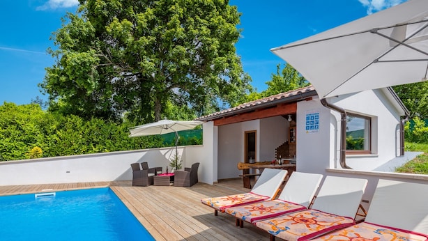 A swimming pool with lounge chairs and a table, surrounded by a wooden deck and a small building with a tiled roof. - Modern Holiday Home With Pool in Pazin (Pazin)