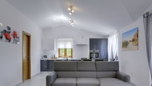 A modern living room with a grey sectional sofa, a kitchen with white cabinets, and a dining area with a table and chairs. - Modern Holiday Home With Pool in Pazin (Pazin)