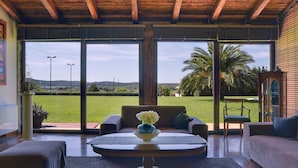 A spacious living room with a large sliding glass door leading to a lush garden and a view of hills. - Luxurious Villa in Pomer with Pool & Hot Tub (Medulin)