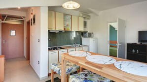 Et moderne køkken med et træspisebord, hvide skabe og en mikrobølgeovn.