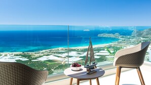 A balcony with a clear view of the ocean and a small sailboat model on a table. - Scenic Villa With Private Pool (Kissamos)