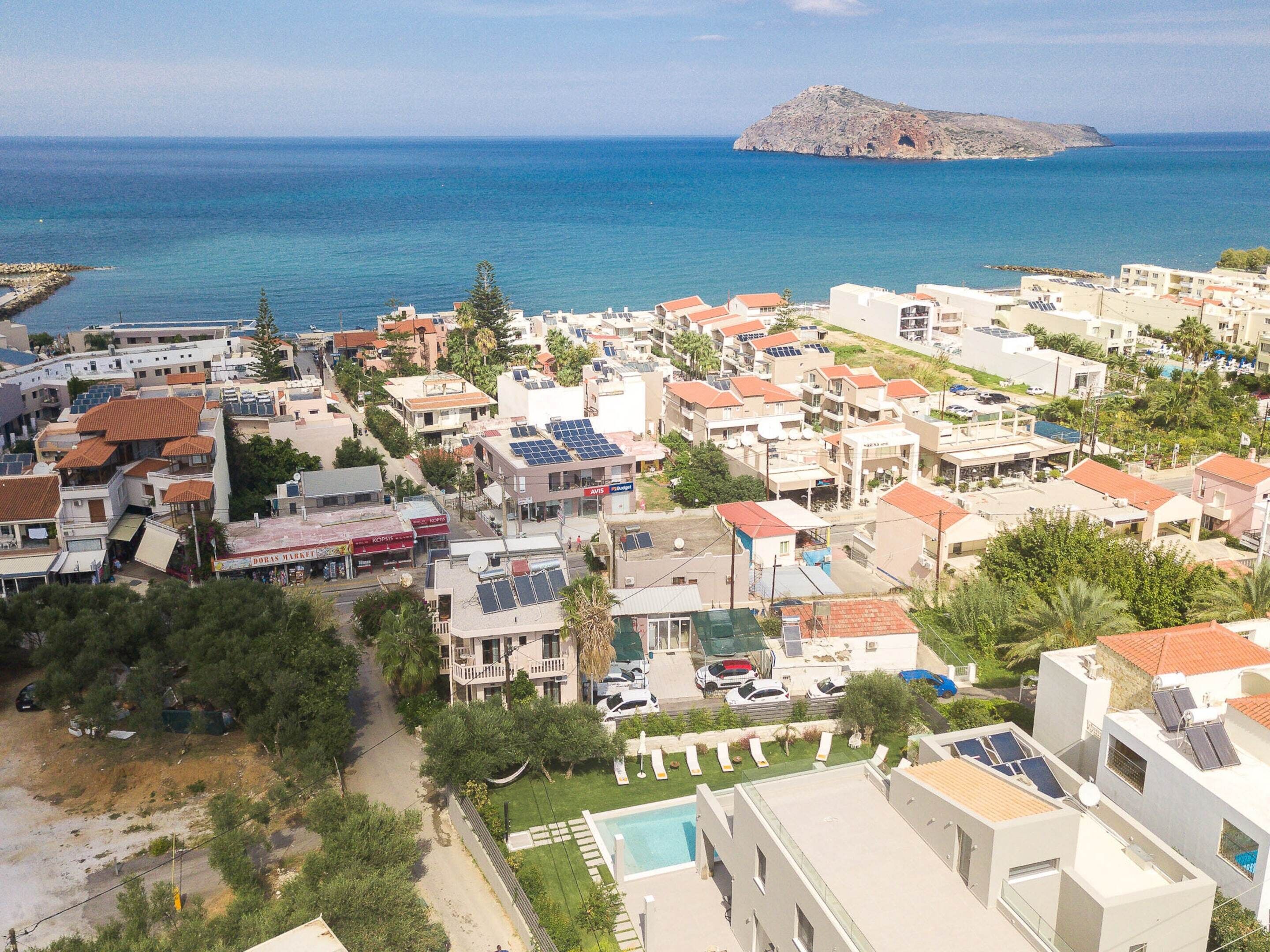 Un quartier résidentiel en bord de mer, avec des immeubles modernes, une piscine et une vue sur la mer et une petite île.