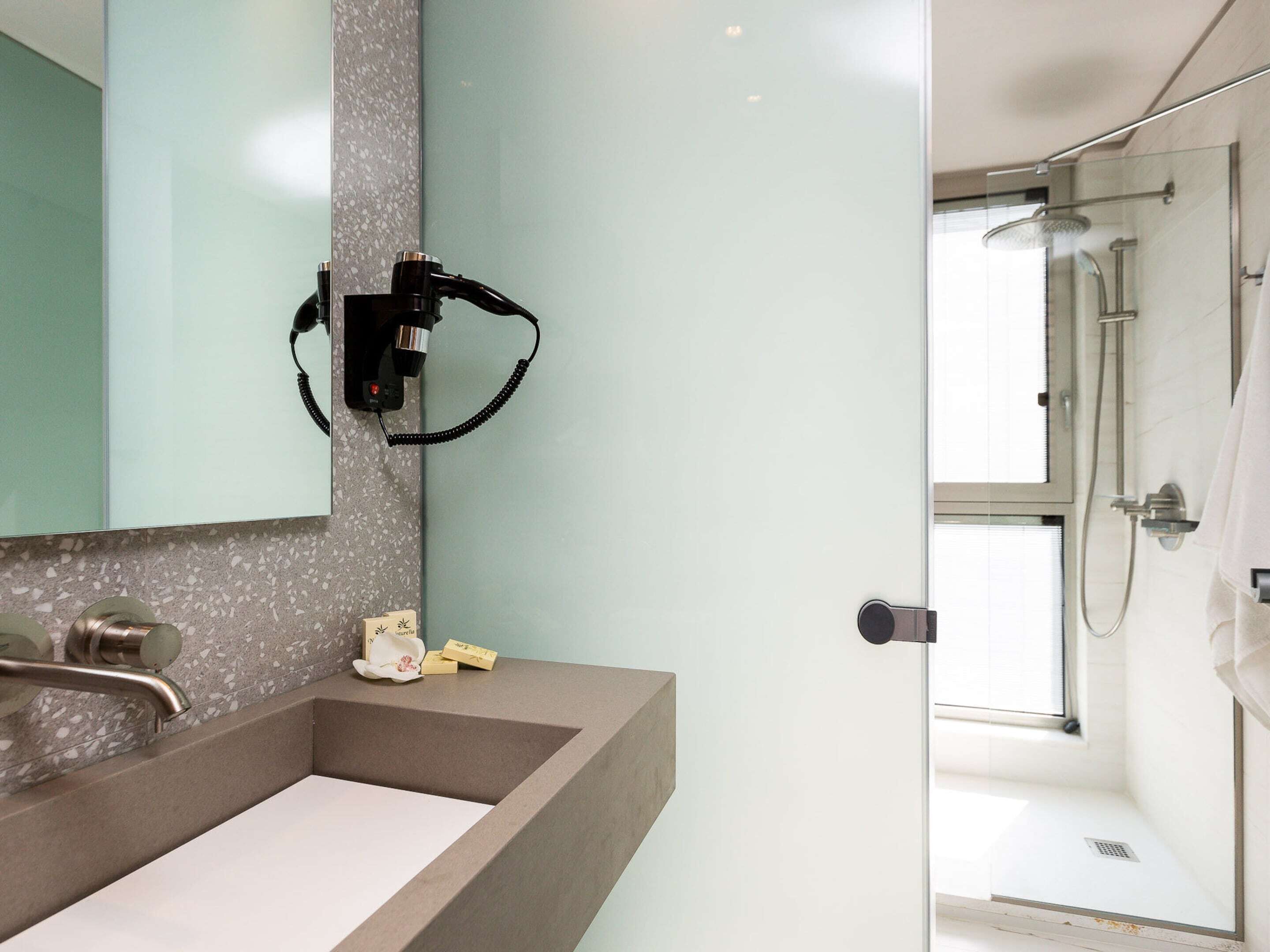 A modern bathroom with a large sink, a mirror, and a shower area.