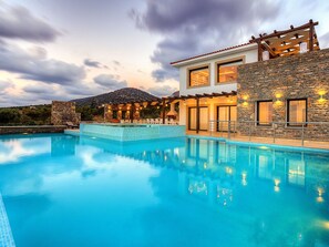 A modern poolside area with a clear pool, stone walls, and a view of a mountain. - Great Villa, Enormous Pool, Nice Location near Village Sisi (Agios Nikolaos)