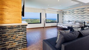 Une chambre moderne avec un grand lit, un mur en pierre et une vue sur la mer.