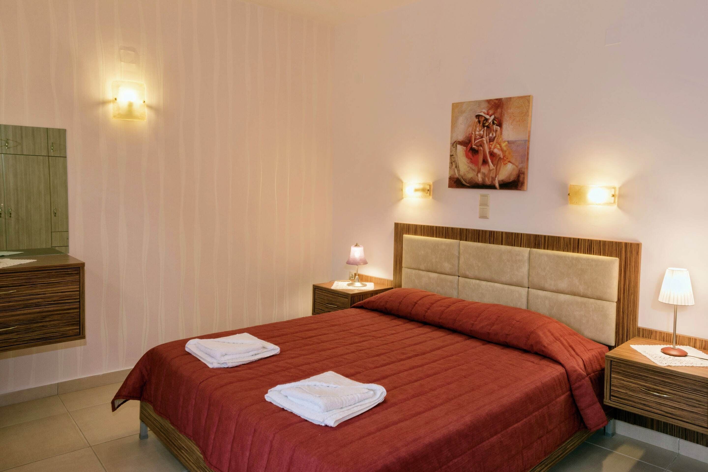 Ein Hotelzimmer mit einem großen Bett, zwei Nachttischen mit Lampen, einem Bild an der Wand und einem Holzschrank.