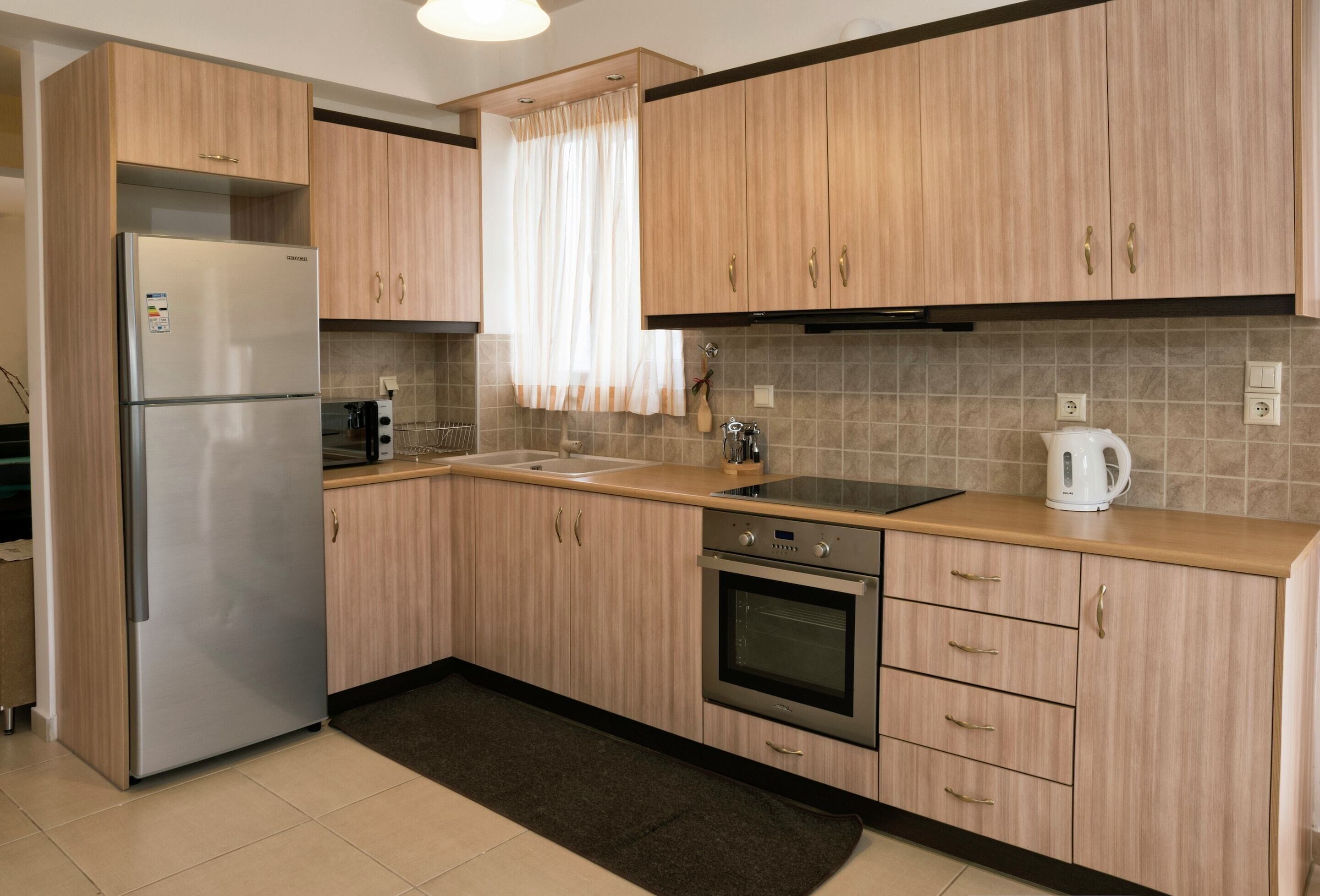 Eine moderne Küche mit Holzausstattung, einem Edelstahlkühlschrank, einem Einbauofen und einem Spülbecken.