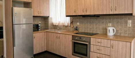 Eine moderne Küche mit Holzausstattung, einem Edelstahlkühlschrank, einem Einbauofen und einem Spülbecken.