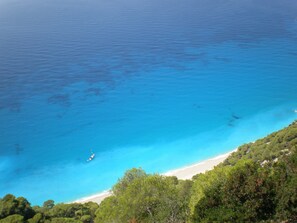 A coastal landscape with a clear blue sea, a sandy beach, and dense green foliage. - Spacious Villa in Vasiliki with Swimming Pool & Hot Tub (Lefkada)