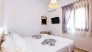 Una camera da letto con un letto, comodini, uno specchio, una TV e una finestra con tende.