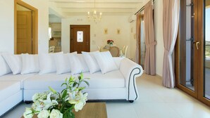 A modern living room with a white sofa, a wooden coffee table, and a chandelier. - Splendid Villa in Achlades with Private Pool near Bali (Mylopotamos)