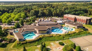 A large hotel complex with multiple swimming pools, a tennis court, and a parking area. - Hotel Room (Arcen)