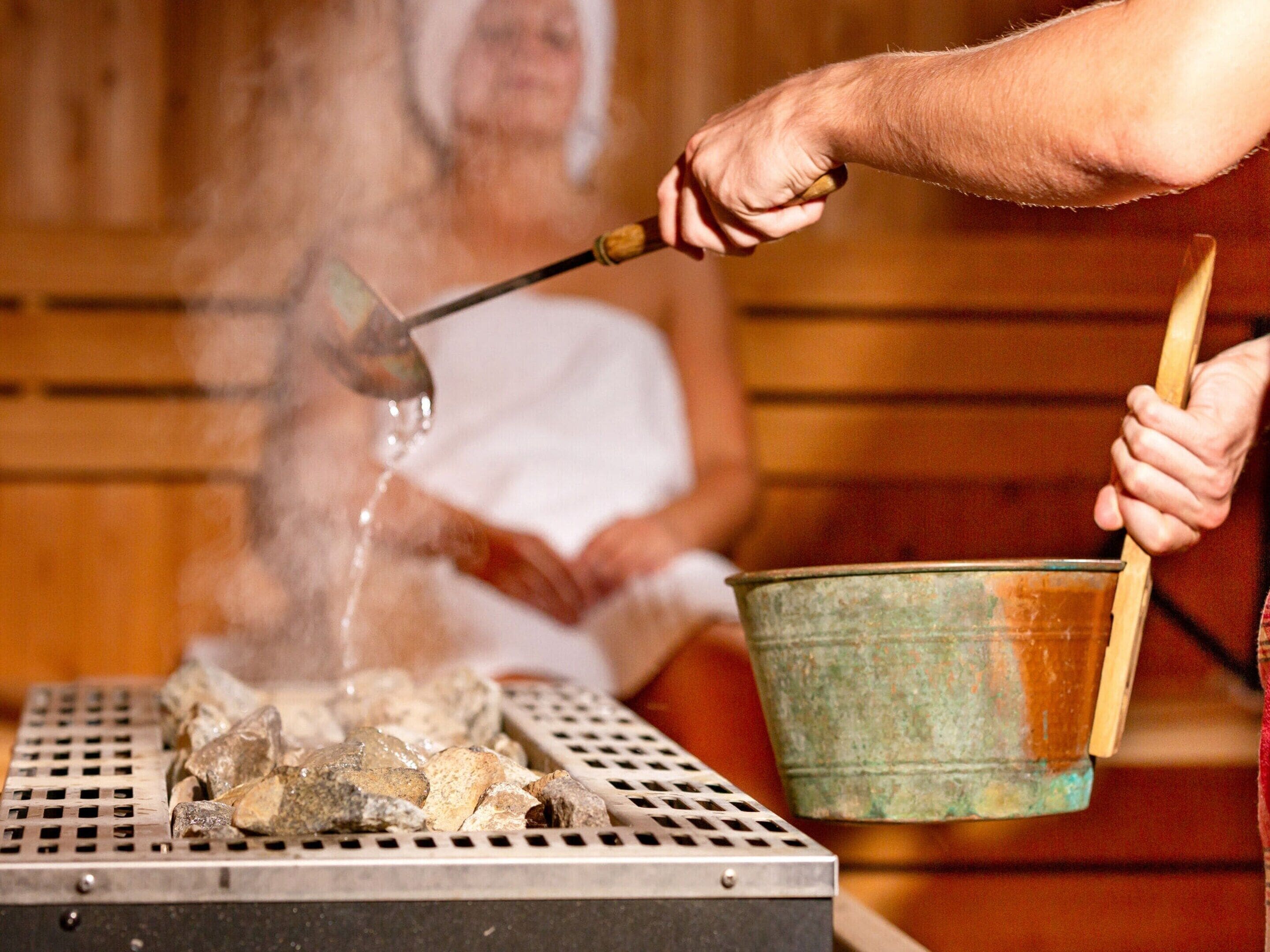 Un sauna avec une grille en métal, des pierres et un seau.
