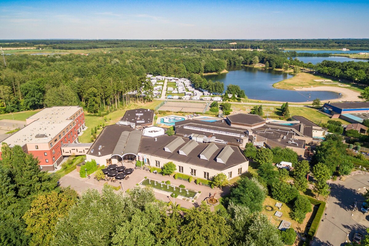 An aerial view of a hotel with multiple buildings, a swimming pool, and a lake in the background.
