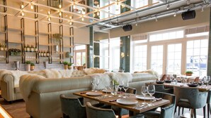 A modern dining area with a sofa and dining tables, surrounded by chairs.