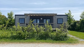 A modern two-story building with a wooden deck and large windows. - Chalet in Friesland Near Nature Reserves (De Veenhoop)