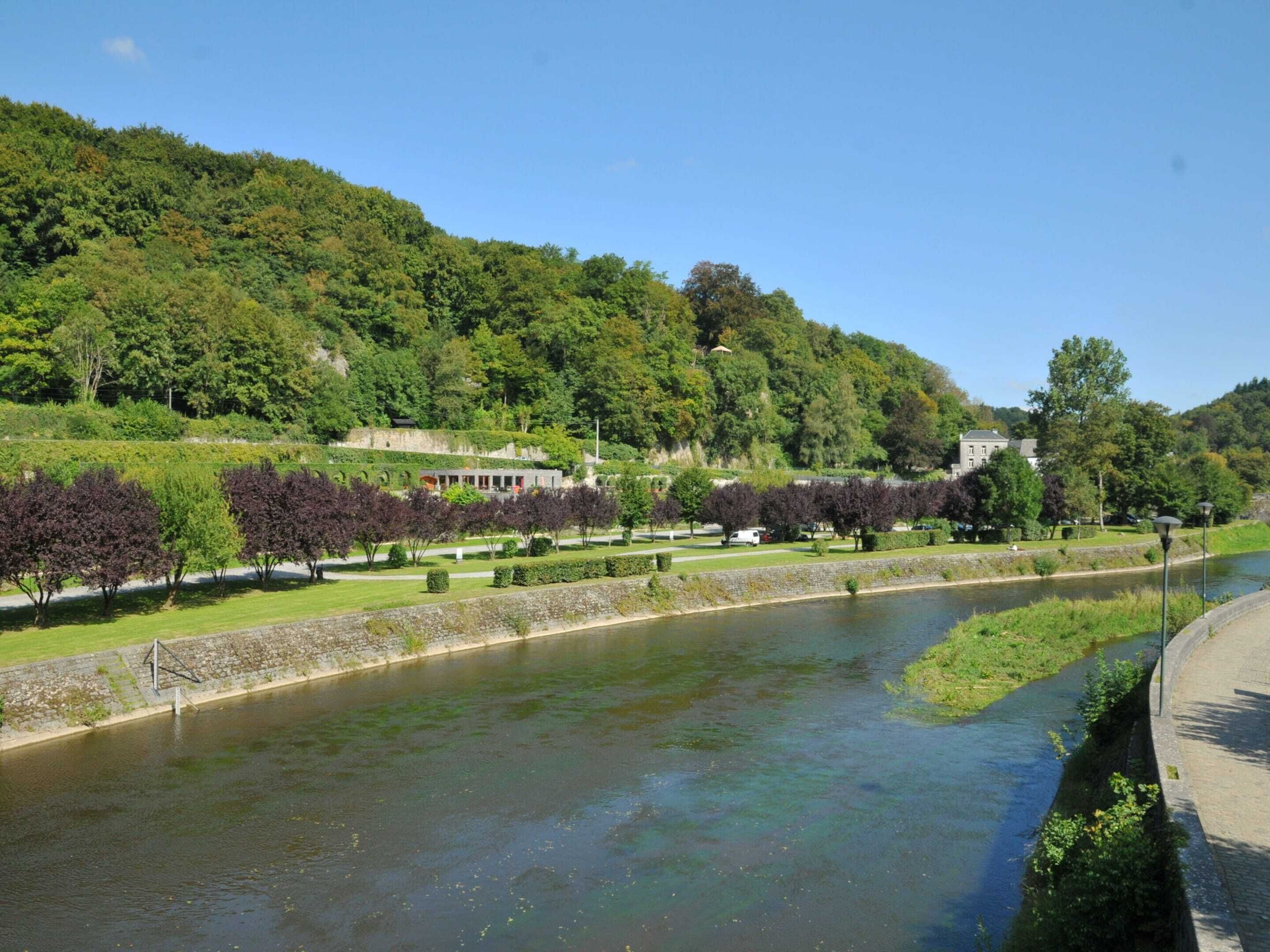 A river with a stone wall and trees along the banks.