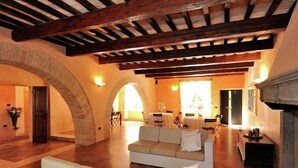 A spacious living area with a high wooden ceiling, a fireplace, and a dining area with tables and chairs. - Villa in Montemaggiore With Private Pool (Colli al Metauro)