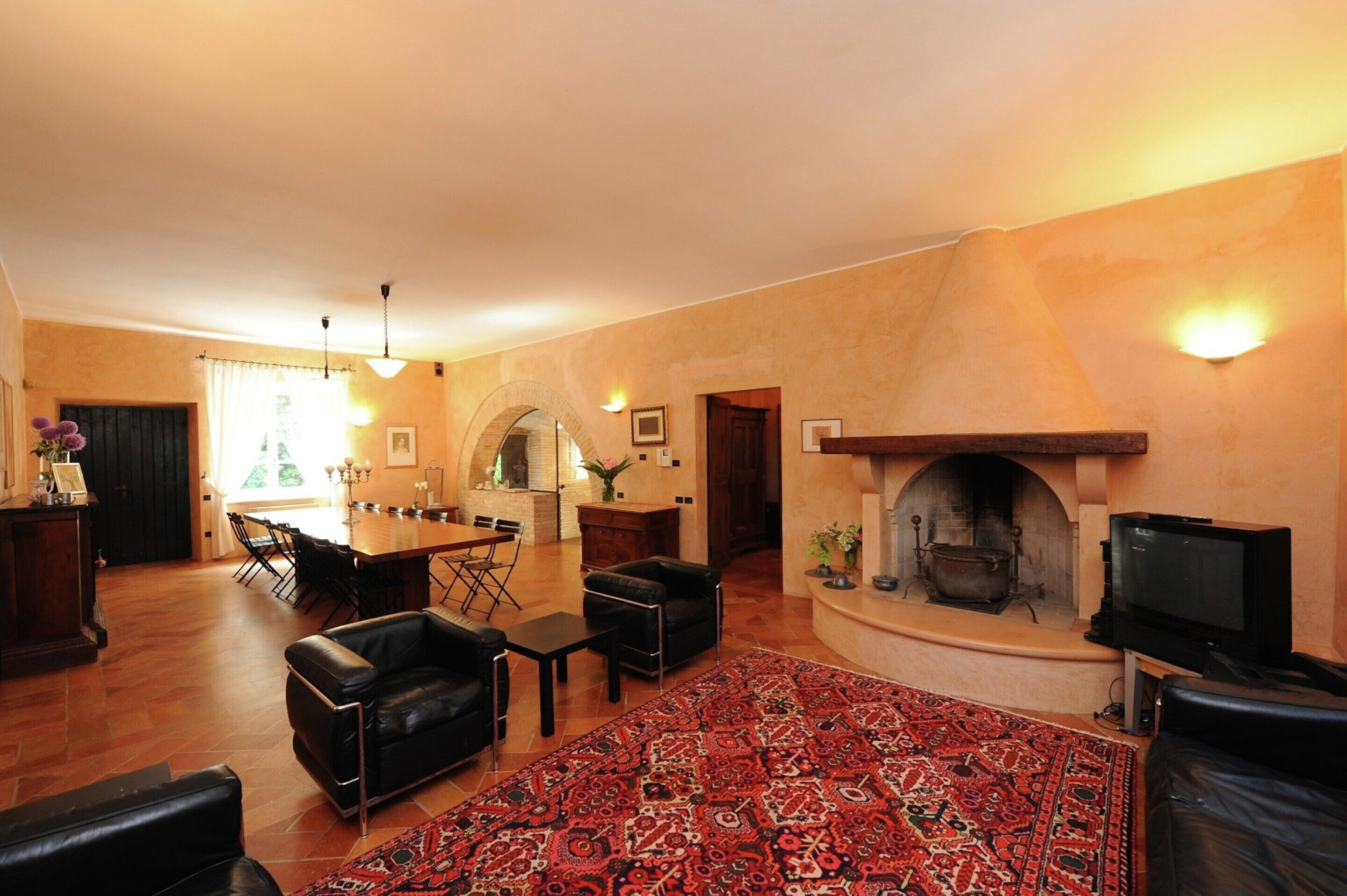Una sala de estar con chimenea, sofás de cuero, un comedor y un televisor.