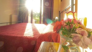 A bedroom with a bed, a vase with flowers, and a view of the outdoors. - Cozy Apartment With Terrace in Tuscany (Capannoli)