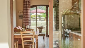 A dining area with a table, chairs, and a view of the outdoors through a glass door. - Cozy Apartment With Terrace in Tuscany (Capannoli)