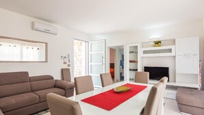 Un salon moderne avec une table à manger blanche, un canapé marron et une cheminée.